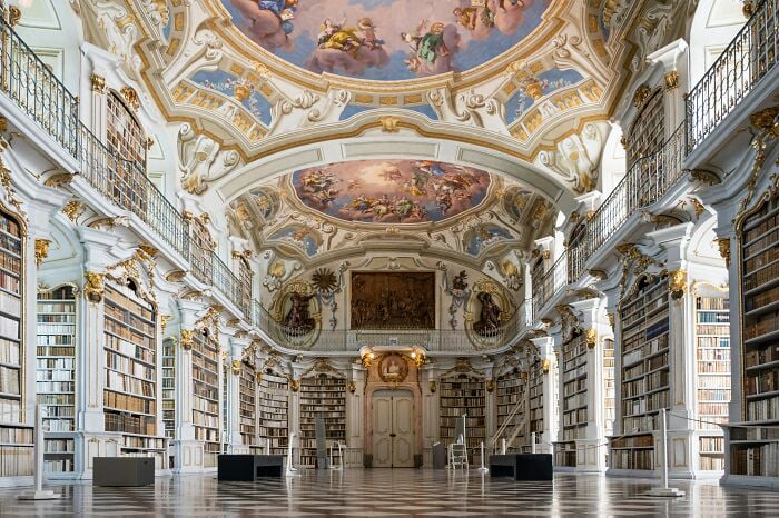 Grandiose Bibliothek mit kunstvollen Decken und hohen Bücherregalen, gefüllt mit Büchern in einer magischen Atmosphäre.